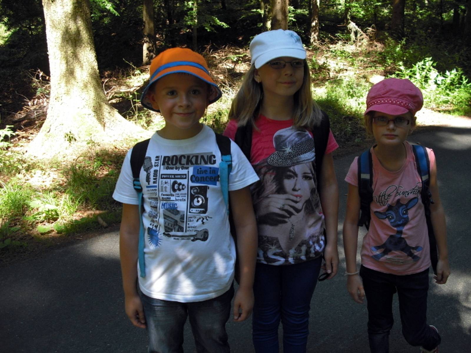 Ein Junge und zwei Mädchen auf einer Wanderung im Wald.