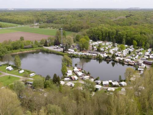 Luftaufnahme eines Natursees mit Gebäuden, Wohnwagen und Wald