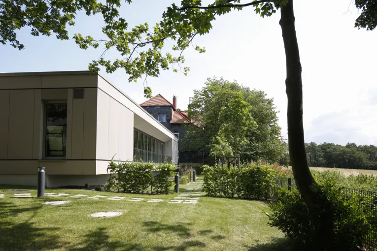 Multifunktionsgebäude im Vordergrund, im Hintergrund sieht man das Haus Humme mit grauer Schieferfassaden