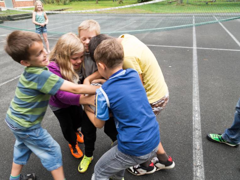  Jungen und Mädchen "kämpfen" um ein Rugby-Ei. 