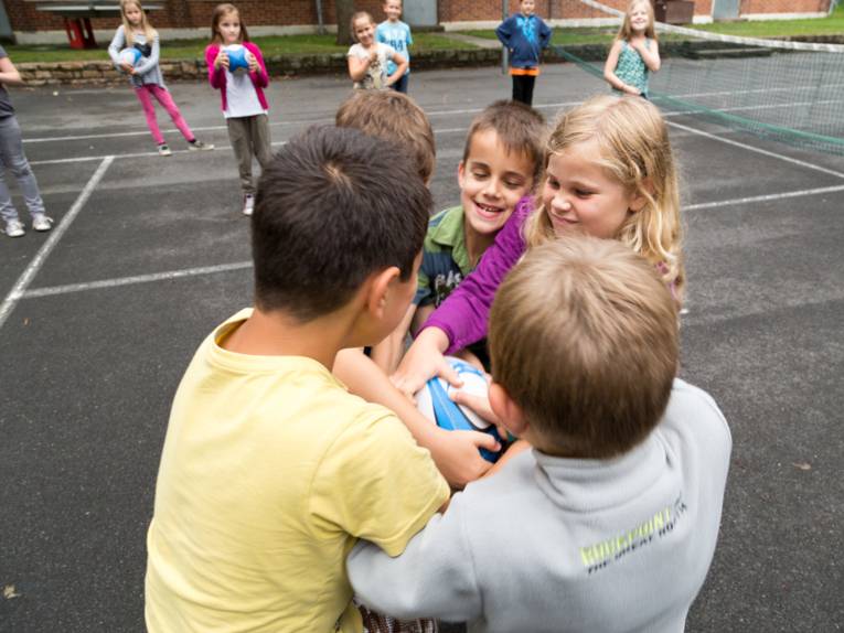 Jungen und Mädchen "kämpfen" um ein Rugby-Ei.