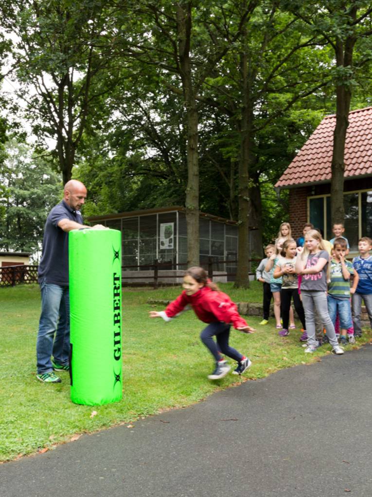 Ein Mädchen schmeisst sich an einen Rugby-Dummy.