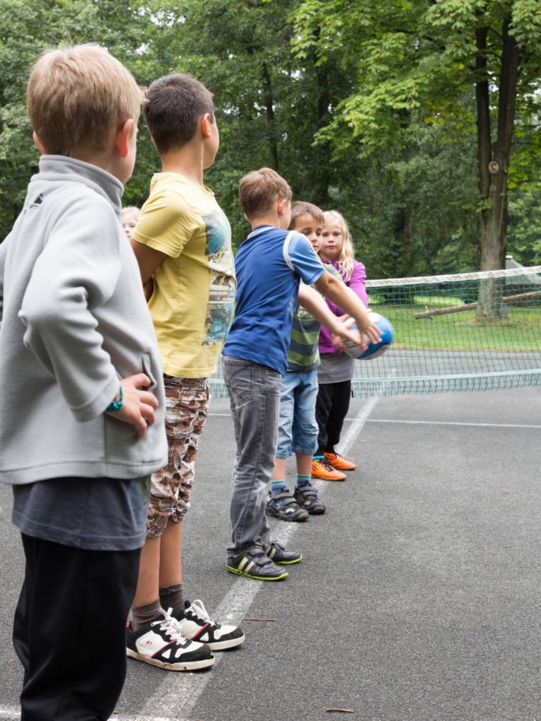 Kinder üben mit einem Rugby-Ei das Pässe werfen.